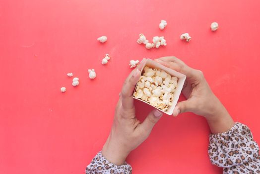 popcorn spilling from a container on red background .