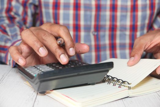 Close up of man hand using calculator.