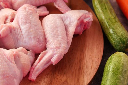 Raw chicken wings with vegetables on table