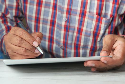 man's hand working on digital tablet at office desk, digital pen