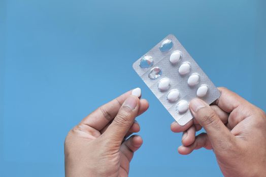 hand holding blister pack isolated on blue .