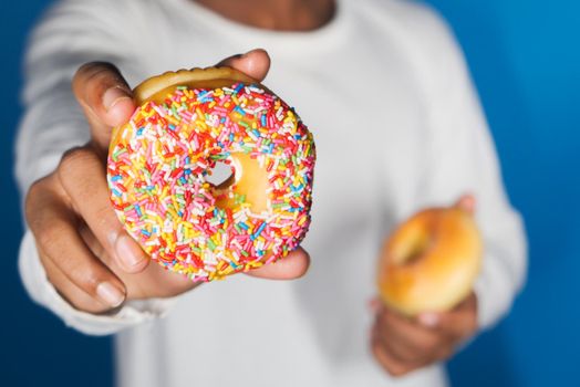 selective focus, Close up of hand holding donuts on blue background .