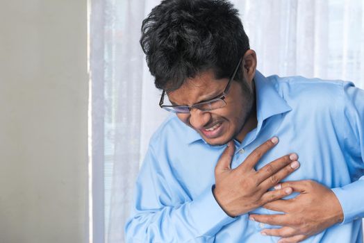 young man suffering pain in heart and holding chest with hand .