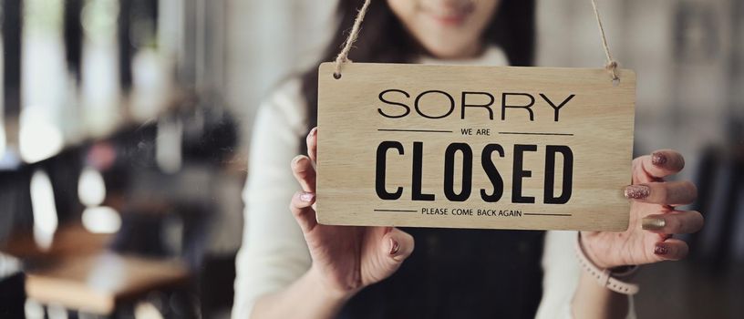 Small business owner turning closed sign board on the entrance door.