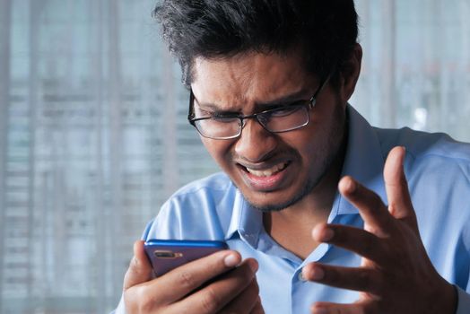 upset man reading bad news on smart phone .