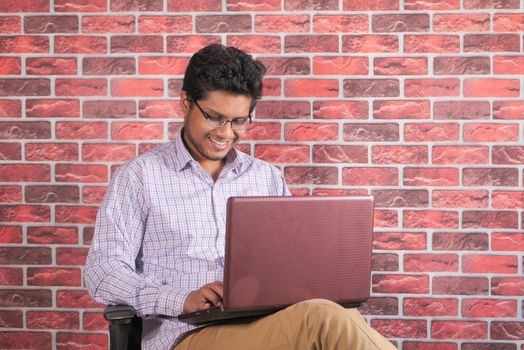 young man sitting on chair using laptop .