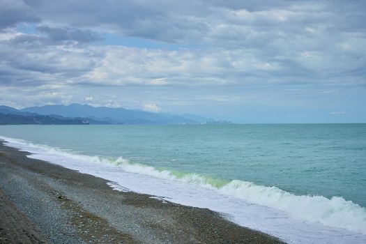 Sea shore with pebbles, wet sea pebbles on the beach and quiet sea surf. Restless sea and waves