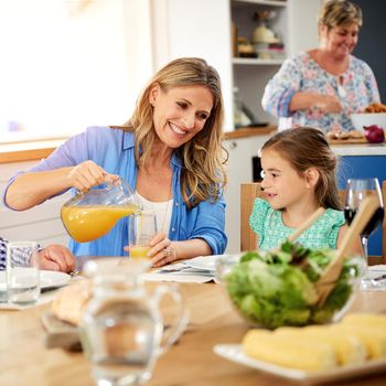 Special mealtime moments. a mother pouring juice into a glass for her little daughter at home