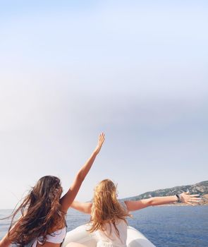 Beautiful girl friends arms raised travel on speed boat to paradise island for relaxing nature tourist destination vacation discover explore.