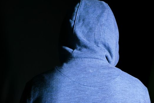sad man in hood cover face with hands isolated in black
