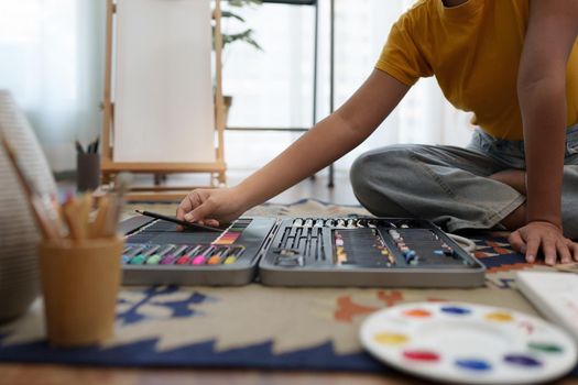 Joyful young female artist choosing colour pencil at workshop.