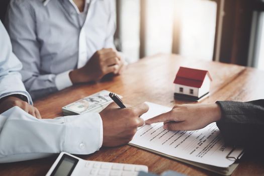 A couple is reading a home purchase contract before signing documents with a real estate agent.