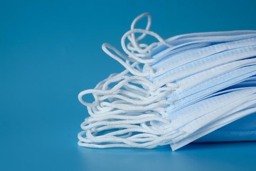 Close up of blue surgical masks on blue background .