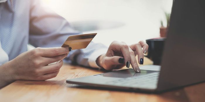 Hands holding credit card, typing on the keyboard of laptop, onine shopping detail close up.