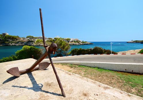 Wide angle view of big iron anchor near harbor of Porto Cristo town in Majorca island, Spain.