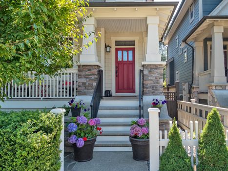 Porch and entrance door of a nice residential house with two flower pots in front.