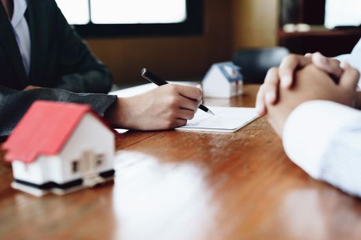 A couple is reading a home purchase contract before signing documents with a real estate agent.