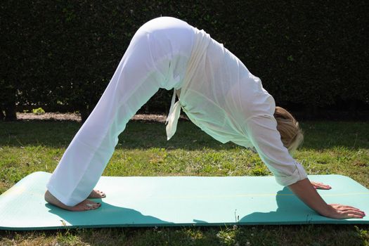 middle aged caucasian doing yoga in the garden in summer sporty lifestyle at any age. High quality photo