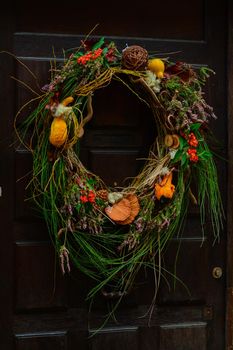 Handmade wreath of zucchini mushrooms cones hanging on a brown vintage door