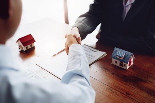 Real estate agents shake hands with customers after signing documents.