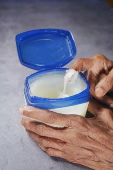 senior woman using petroleum jelly onto skin at home close up.