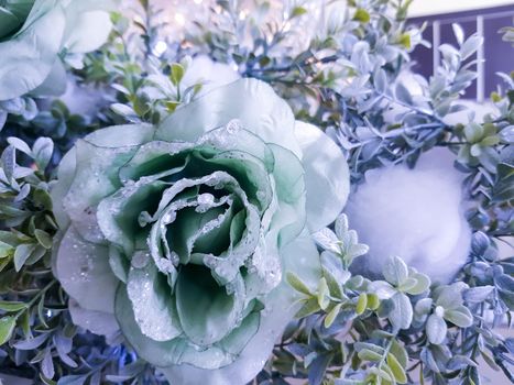 Frozen rose in white frost. Rose petals in small ice crystals surrounding a flower, decorative decoration of a Christmas tree, selective focus.