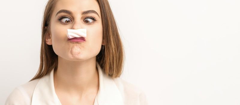 Young funny woman with sweet candy marshmallow-like mustache over white background. Depilation and epilation concept