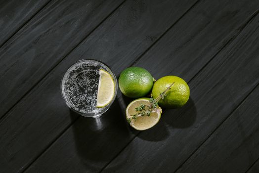 gin and tonic with citrus fruit and thyme on a black background.