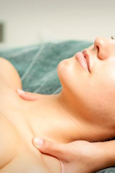 Side view hands of female therapist making massage of neck and shoulders to young caucasian woman in spa beauty salon