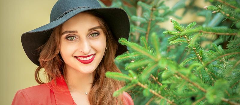 Portrait of a beautiful young caucasian woman with Christmas tree smiling and looking at camera