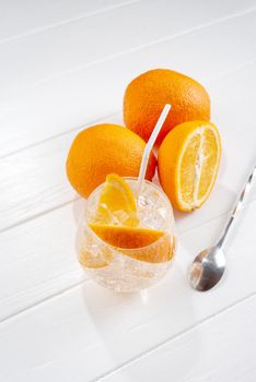 Cold fresh orange lemonade on wooden light background.