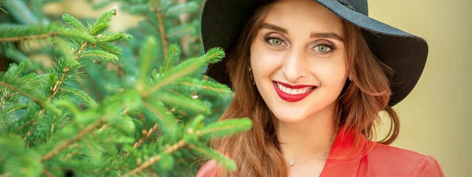 Portrait of a beautiful young caucasian woman with Christmas tree smiling and looking at camera