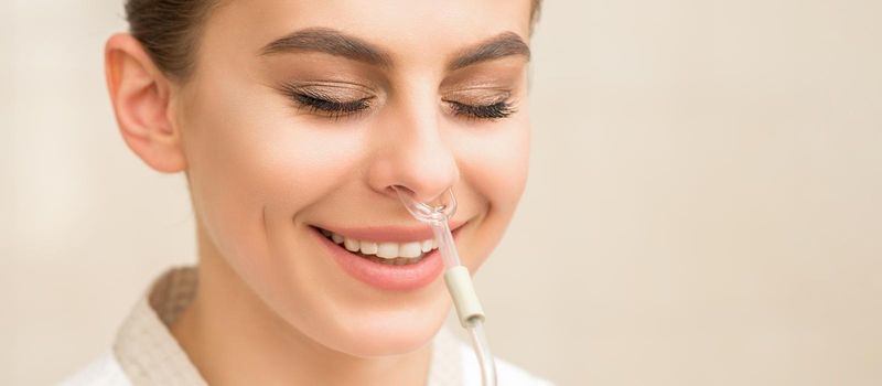 Beautiful happy young caucasian woman receiving nasal inhaler with essential oil smiling in a spa