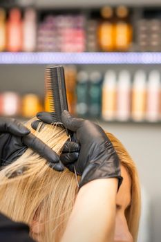 Hairdresser combing client's female hair before dyeing hair in a hair salon
