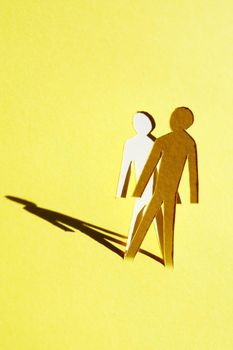 Man figure cutting from yellow paper with long shadow