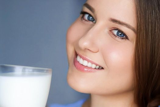 Happy young woman with glass of milk or protein milk shake, healthy cocktail drink for diet and wellness concept