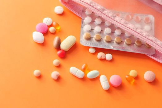 birth control pills on orange background, close up .