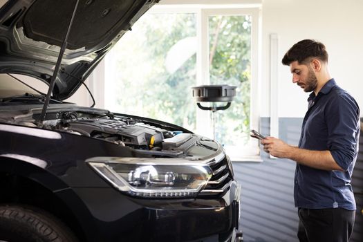 Specialist Inspecting Engine in Order to Find Broken Components. Shot for Animation of Car Service Manager Uses Tablet Computer with Futuristic Augmented Reality Diagnostics Software.