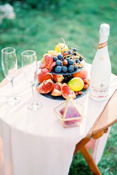 Stand with fruit, glasses and a bottle of champagne are on the table. High quality photo