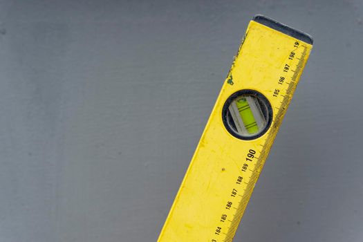 iron yellow bubble Building level with length markings on a grey background in the workshop. Close-up. Copy space. Ruler. Building and engineering equipment. Measure. Construction bubble level