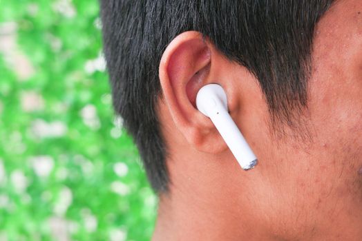 young man putting wireless hear phone close up .