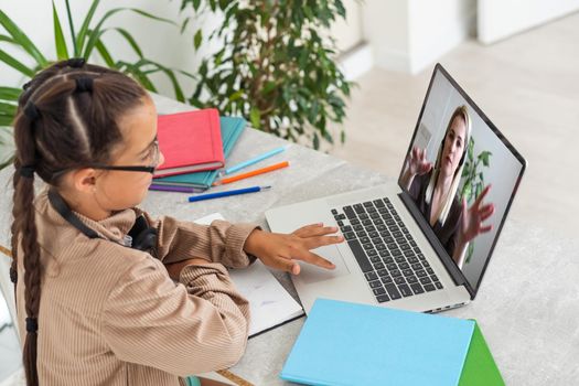 E-Learning. Shocked Little Schoolgirl Looking At Laptop Wearing Headphones Looking At Computer Web Camera In Shock Making Video Call And Learning Online At Home. Shocking News Concept