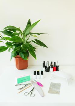 Nail salon workspace concept. Top view female hands and manicure tools on pink background. Beauty treatment and hand care