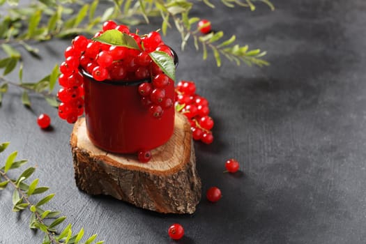 Red currant in a mug on a black background. copy space