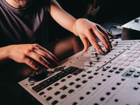 Unrecognizable sound producer or engineer rotates scrolls wheel on mixing console in professional recording studio. Musician working on new song. Hands close up. High quality photo