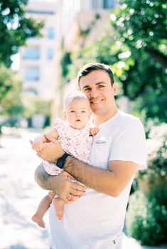 Smiling dad holds a little girl in his arms on the street. Portrait. High quality photo