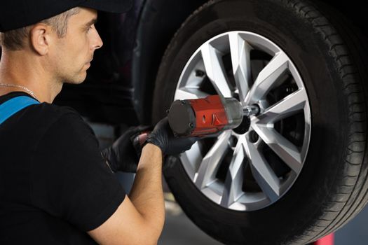 Assembly or dismantling of the wheels in the workshop. repair and maintenance of the car in service. Car mechanic replacing car wheel of lifted automobile at repair service station.