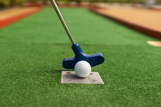 A club prepares to hit a ball during a mini golf game.