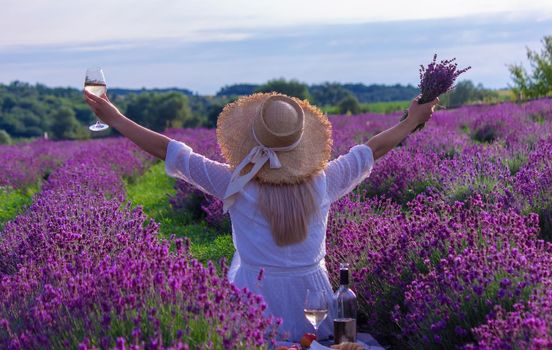 a girl in a lavender field pours wine into a glass. Relaxation. selective focus