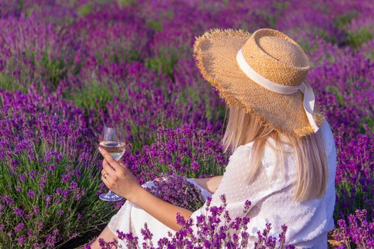 a girl in a lavender field pours wine into a glass. Relaxation. selective focus
